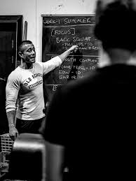 A coach pointing at a whiteboard program in front of his group